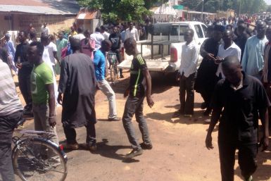 Shiite faithful dressed in black walk at the scene of a suicide blast in the northeast Nigerian town of Potiskum