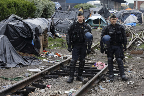 French gendarmes stand guard near makeshift shelters as they evacuated immigrants of an improvised camp in Calais, northern France, May 28, 2014