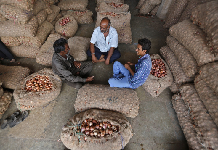 Traders sit amidst stacked sacks, filled with onions and potatoes, at a wholesale vegetable market in the western Indian city of Ahmedabad
