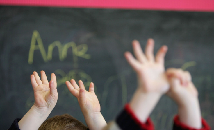 Children in Glasgow raise their hands in class. With their brains malleable, children are able to learn complex skills like language use quickly. (Getty)