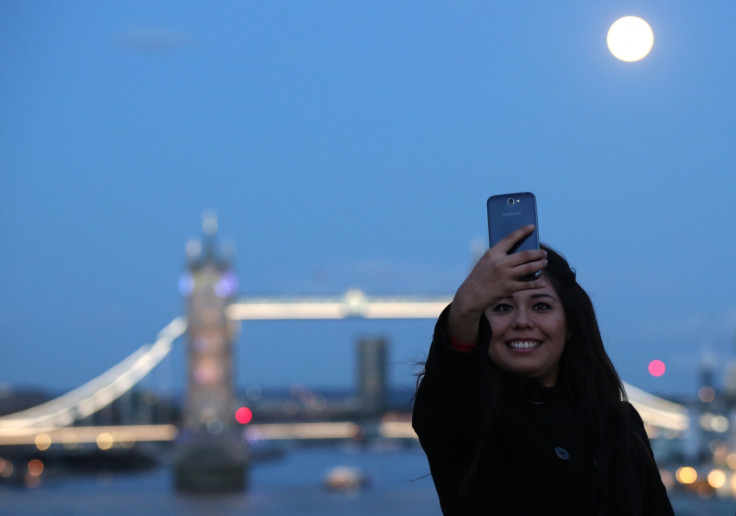 woman takes a selfie as the supermoon rises over Tower Bridge in London