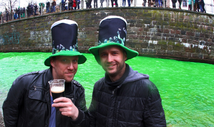 People pose with a Guinness along the river Vilnele as it is colored green to celebrate St Patrick's Day in Lithuania