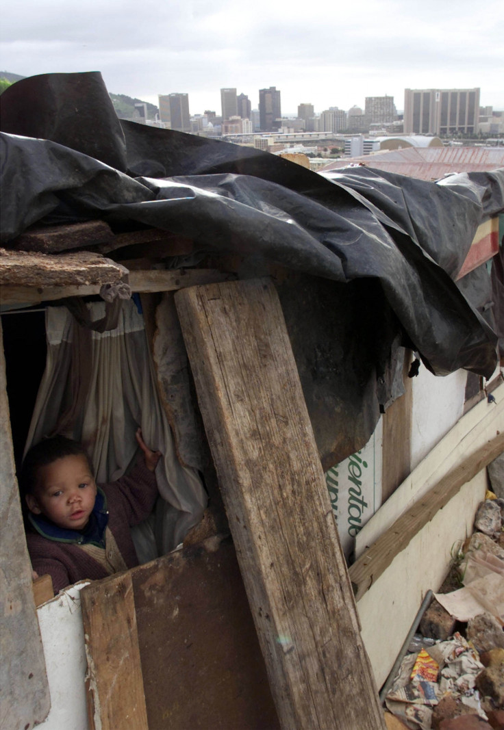 A child peers out from the window of a Cape Town shack