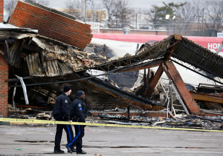 Police officers look over the site of a building that was burned during riots in Ferguson, Missouri