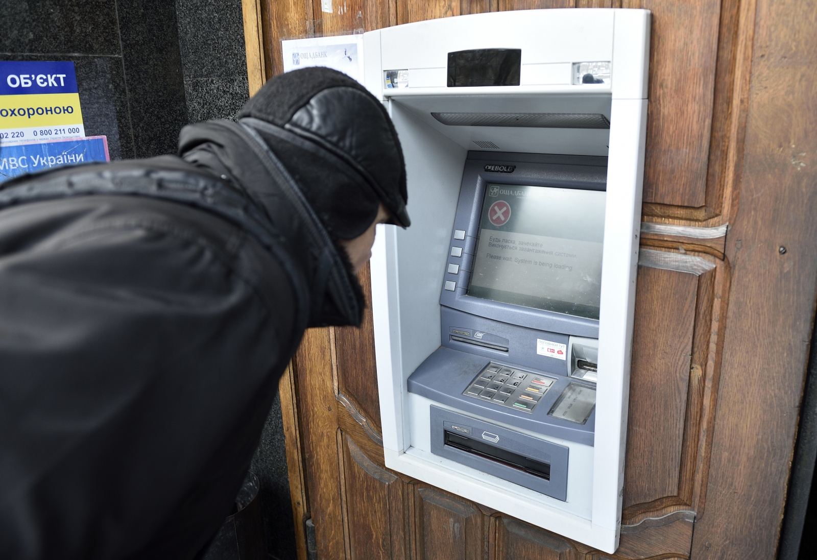 A man stands in front an ATM machine which is out of order, on November 26, 2014 in the eastern Ukrainian city of Donetsk