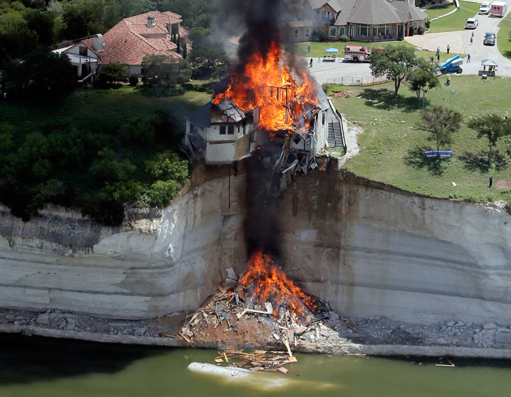 June 13, 2014: Smoke rises from a house days after part of the ground it was resting on collapsed into Lake Whitney, Texas