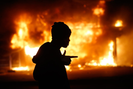 November 25, 2014: A man walks past a burning building during rioting after a grand jury returned no indictment in the shooting of Michael Brown in Ferguson, Missouri