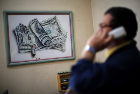A man talks on the telephone, in front of a caricature of dollar bills