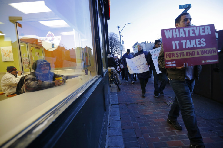 Fast food workers and their supporters calling for a $15 minimum wage walk past a men sitting in a McDonalds restaurant in Chelsea, Massachusetts December 4, 2014