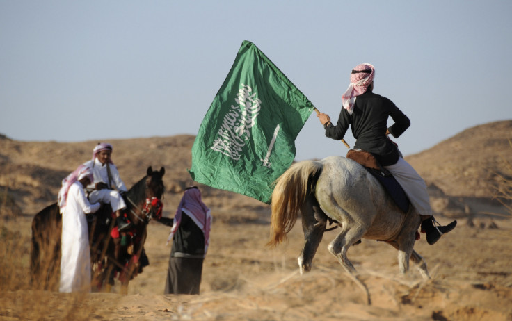 A Saudi man riding a horse waves a national flag