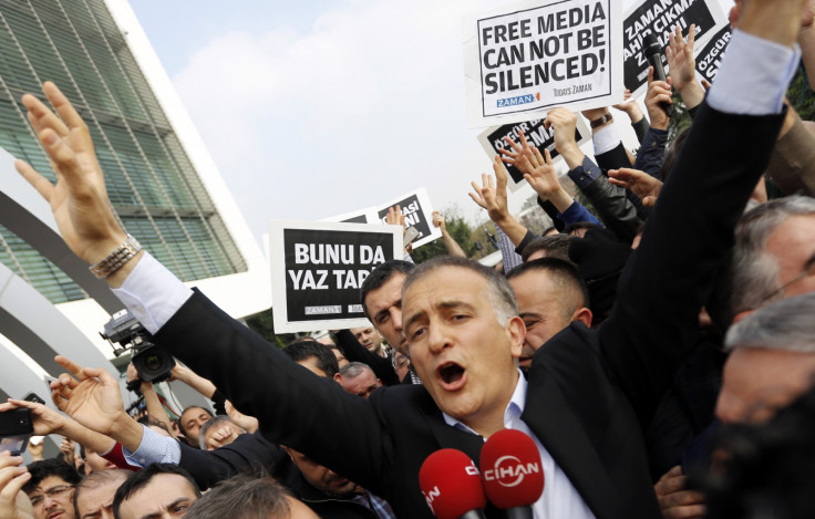 Zaman editor-in-chief Ekrem Dumanli, surrounded by his colleagues and plainclothes police officers (C), reacts as he leaves the headquarters of Zaman daily newspaper in Istanbul Zaman editor-in-chief Ekrem Dumanli, surrounded by his colleagues and plainclothes police officers (C), reacts as he leaves the headquarters of Zaman daily newspaper in Istanbul