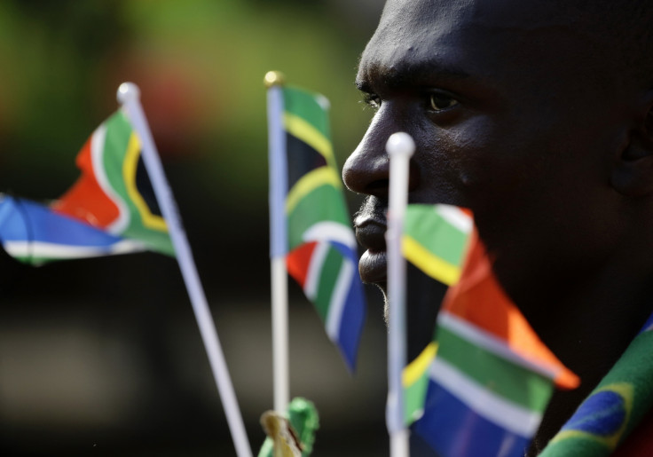 Man holds South African national flags as he waits to view the body of former South African President Nelson Mandela.