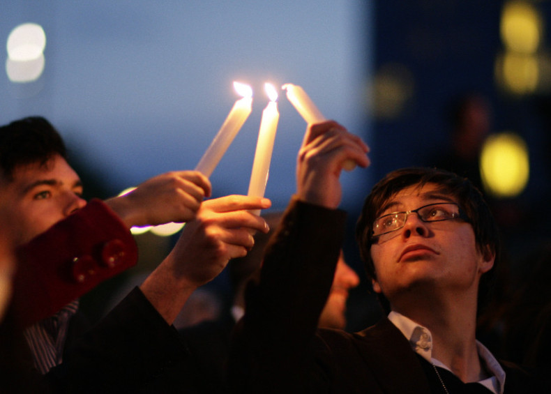Observers light candles during an event to commemorate the Holocaust