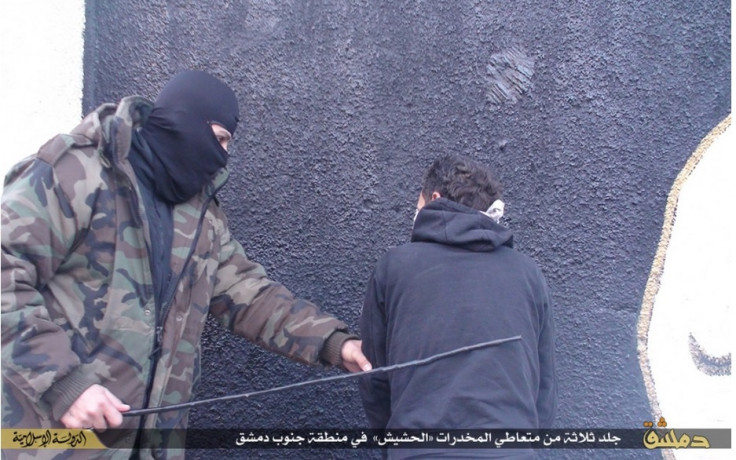 A masked IS fighter is seen whipping one of the drug addicts