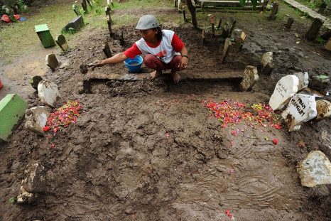 Tomb digger cleans up Hayati Lutfiah Hamid's grave, the first identified victim of the AirAsia flight QZ8501 crash at Sawo Tratap Islamic cemetery on January 2, 2015