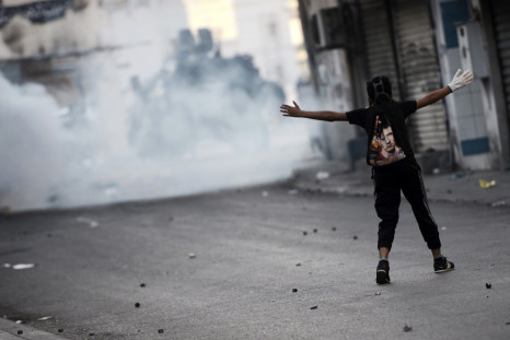 A Bahraini protestor gestures towards riot police during clashes following a protest against the arrest of the head of the banned Shiite opposition movement Al-Wefaq, Sheikh Ali Salman