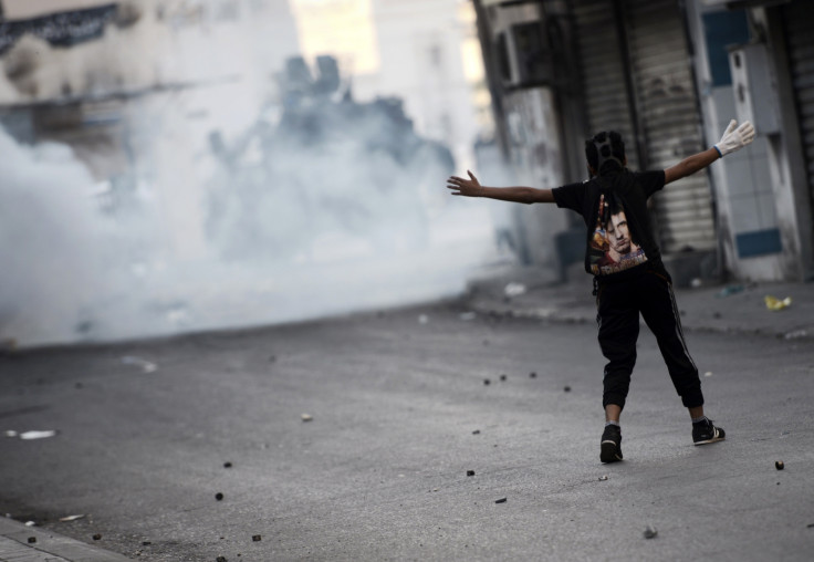 A Bahraini protestor gestures towards riot police during clashes following a protest against the arrest of the head of the banned Shiite opposition movement Al-Wefaq, Sheikh Ali Salman