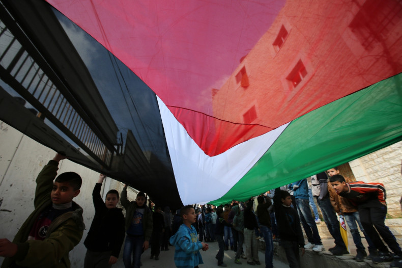 Palestinian children deploy a giant national flag during a march of members of the al-Aqsa Martyrs Brigades, the Palestinian Fatah movement's armed wing, to mark the 50th anniversary of the launching of Fatah's armed struggle against Israel