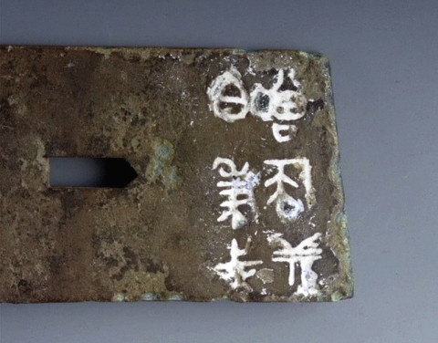 Close-up of the Old Chinese characters inscribed on the metal item
