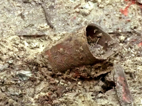 A beautifully inscribed metal object being unearthed from the tomb