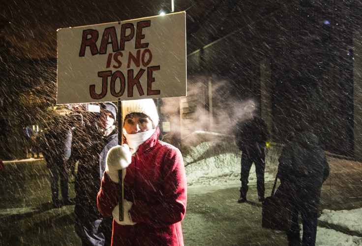 A woman holding a sign that reads "Rape is No Joke" protests as people walk into the Centre In The Square venue where Bill Cosby is performing in Canada