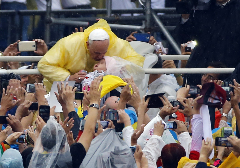 Pope Francis kisses a child as he arrives to lead an open-air Mass at Rizal Park in Manila
