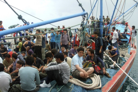 Asylum seekers sit on a fisherman's boat after they were rescued when their boat sunk off Sunda straits