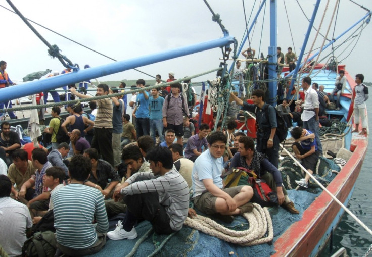 Asylum seekers sit on a fisherman's boat after they were rescued when their boat sunk off Sunda straits