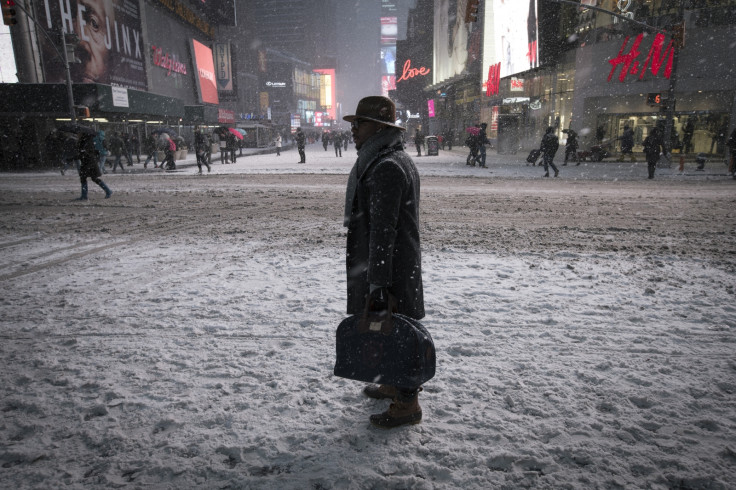 A man stands in falling snow on West 42nd street in Times Square in New York, January 26, 2015.