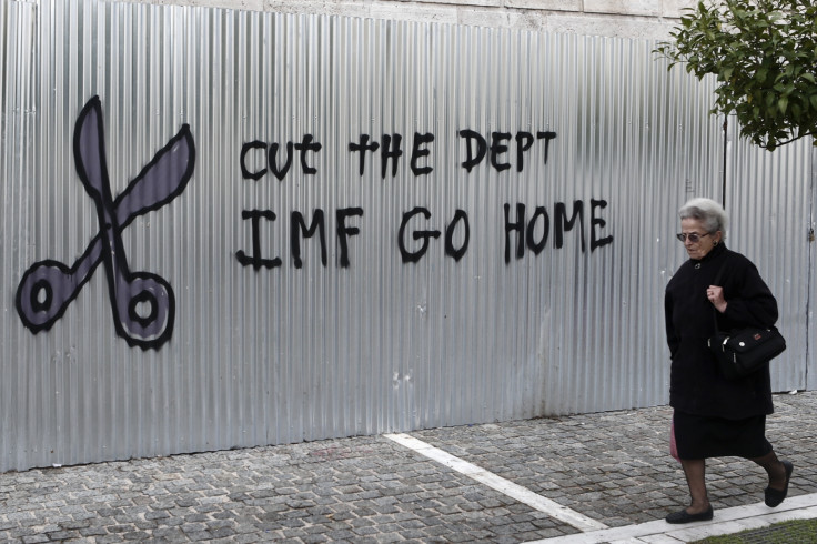 A woman walks past a graffiti that reads "Cut the debt, IMF go home" in Athens January 24, 2015.