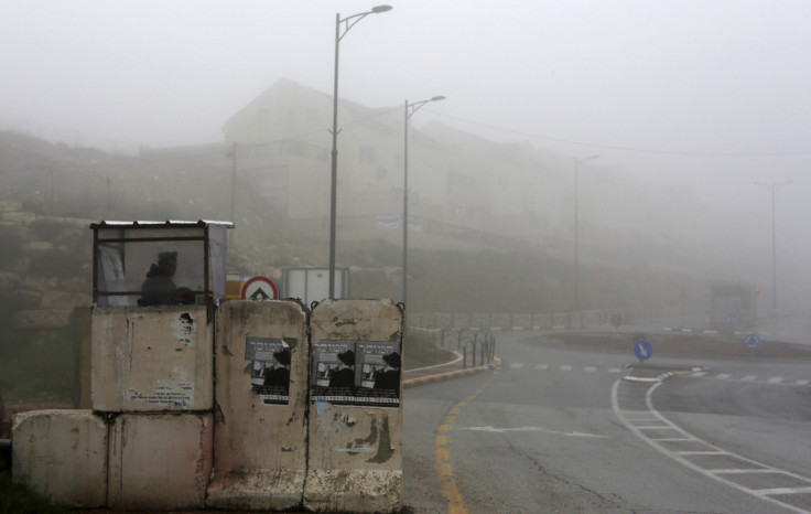 An Israeli soldier stands guard at the entrance to the West Bank settlement of Kiryat Arba