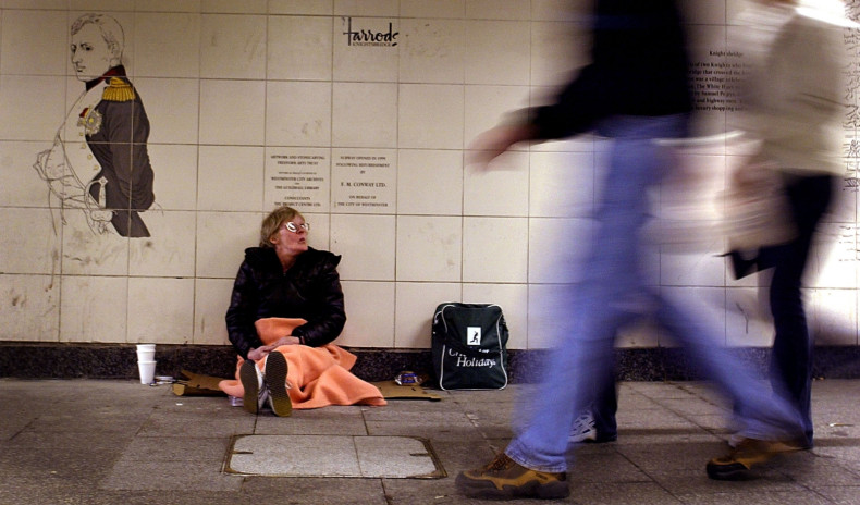 A homeless woman begs for change in a subway station