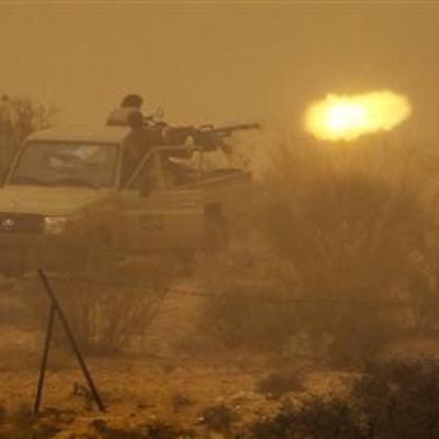 Libyan rebels fire an anti-aircraft gun at government forces during a heavy sandstorm near the village of Tiji in western Libya