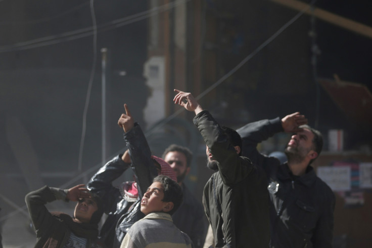 Residents react and gesture to the sky, during what activists said were seven air-strikes by forces loyal to Syria's President Bashar al-Assad, in Duma in Eastern Al-Ghouta