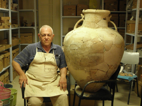 An archaeologist sits next to the large earthenware Cypriot pithoi from 17th century BC that he restored