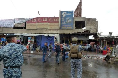 Iraqi police clear pedestrians of a street after a suicide bomber detonated explosives inside a restaurant in Baghdad al-Jadida, east of the capital,