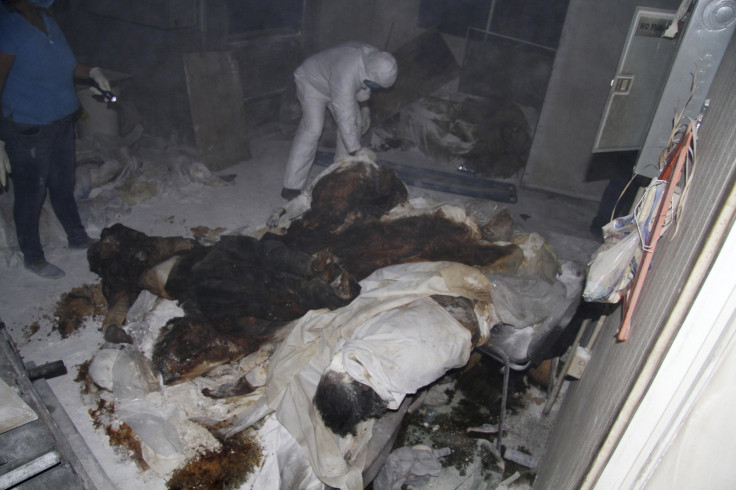 Forensic technicians stand near dead bodies at a crematorium