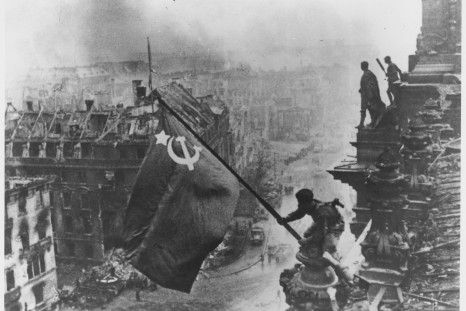 Russian soldiers flying the Red Flag, made from table cloths, over the ruins of the Reichstag in Berlin