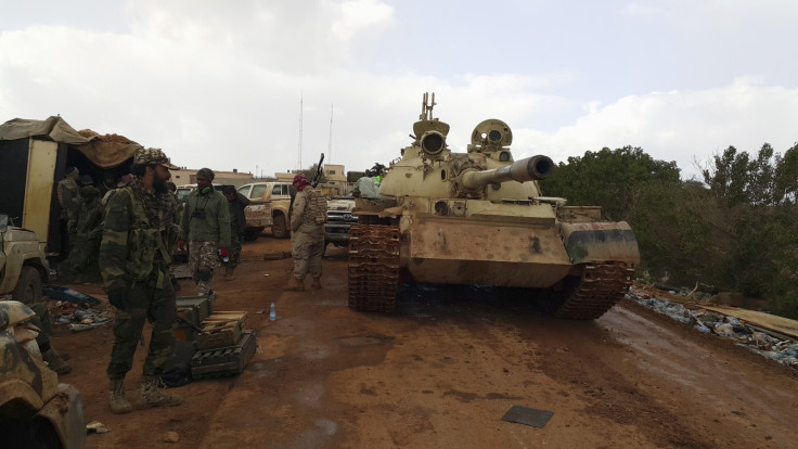 Members of Libyan pro-government forces, backed by locals, stand beside a tank at a rally point during nearby clashes with the Shura Council of Libyan Revolutionaries, an alliance of former anti-Gaddafi rebels who have joined forces with Islamist group An