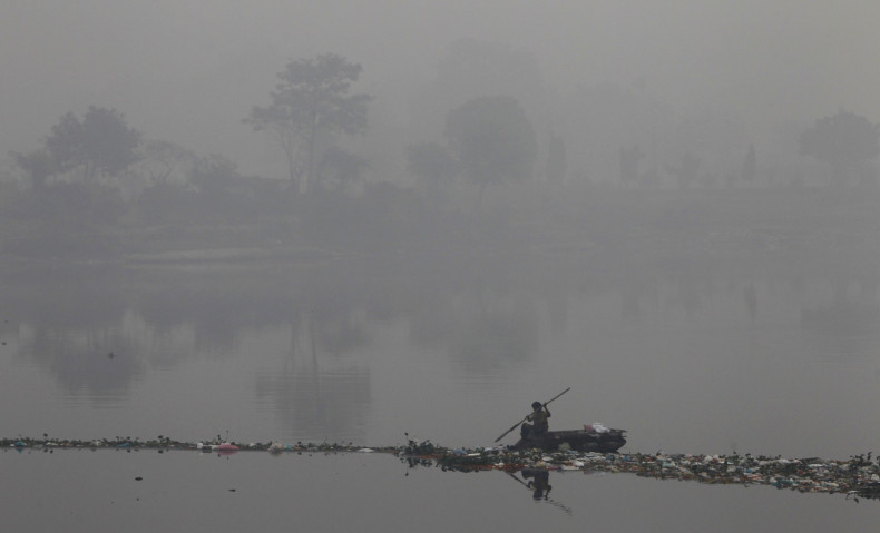 A rag picker collects recyclable materials in the polluted waters of river Yamuna amid dense smog in Delhi.