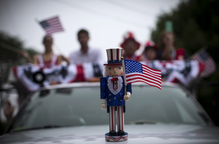 An Uncle Sam figure sits on the hood of a car in a July Fourth parade in the village of Barnstable, Massachusetts