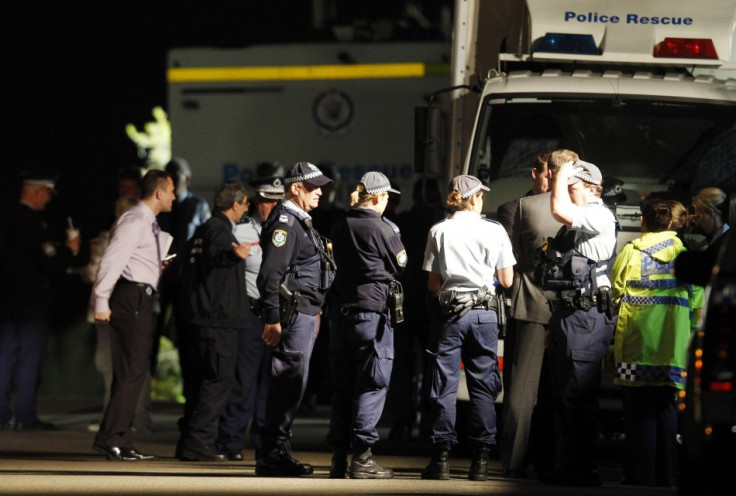 Police and emergency workers stand near a house where bomb squad officers are working in Mosman