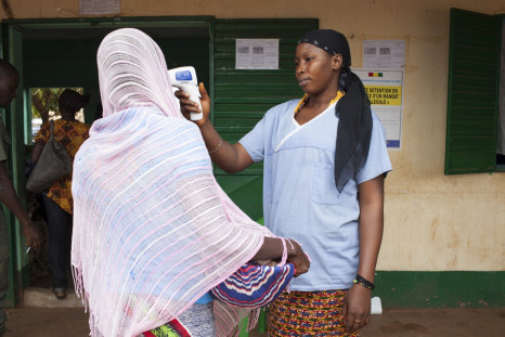 A health worker checks the temperature of a woman leaving Guinea at the border with Mali in Kouremale,