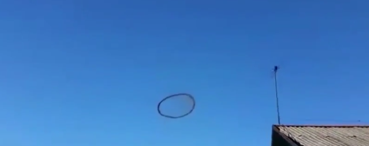 Black ring hovers in sky
