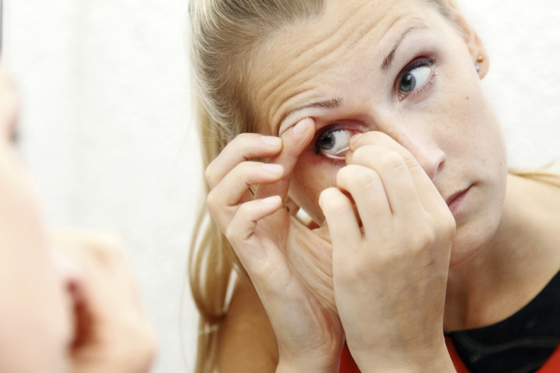 A woman struggles to apply contact lenses