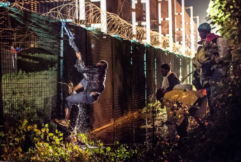 A migrant climbs a security