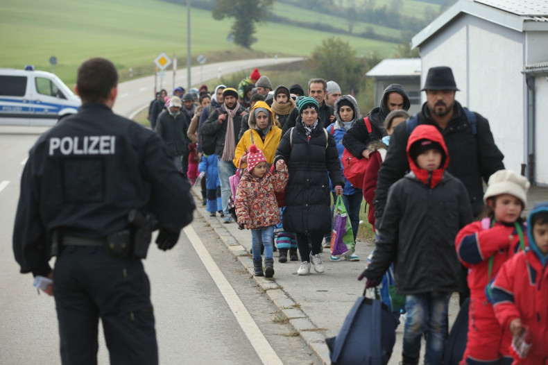 A German policeman directs migrants who had walked across the nearby border from Austria on October 17, 2015 in Wegscheid, Germany.