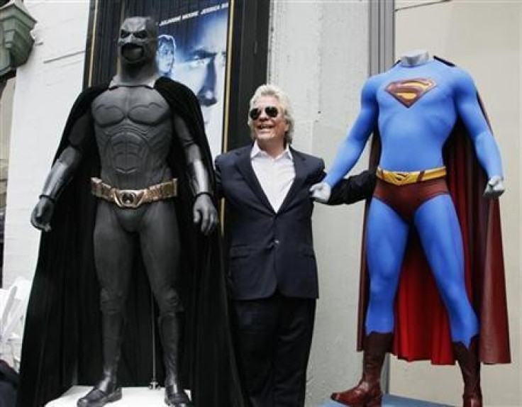 Film producer Jon Peters poses with a Batman (L) and Superman (R) costume after ceremonies unveiling his star on the Hollywood Walk of Fame in Hollywood, California