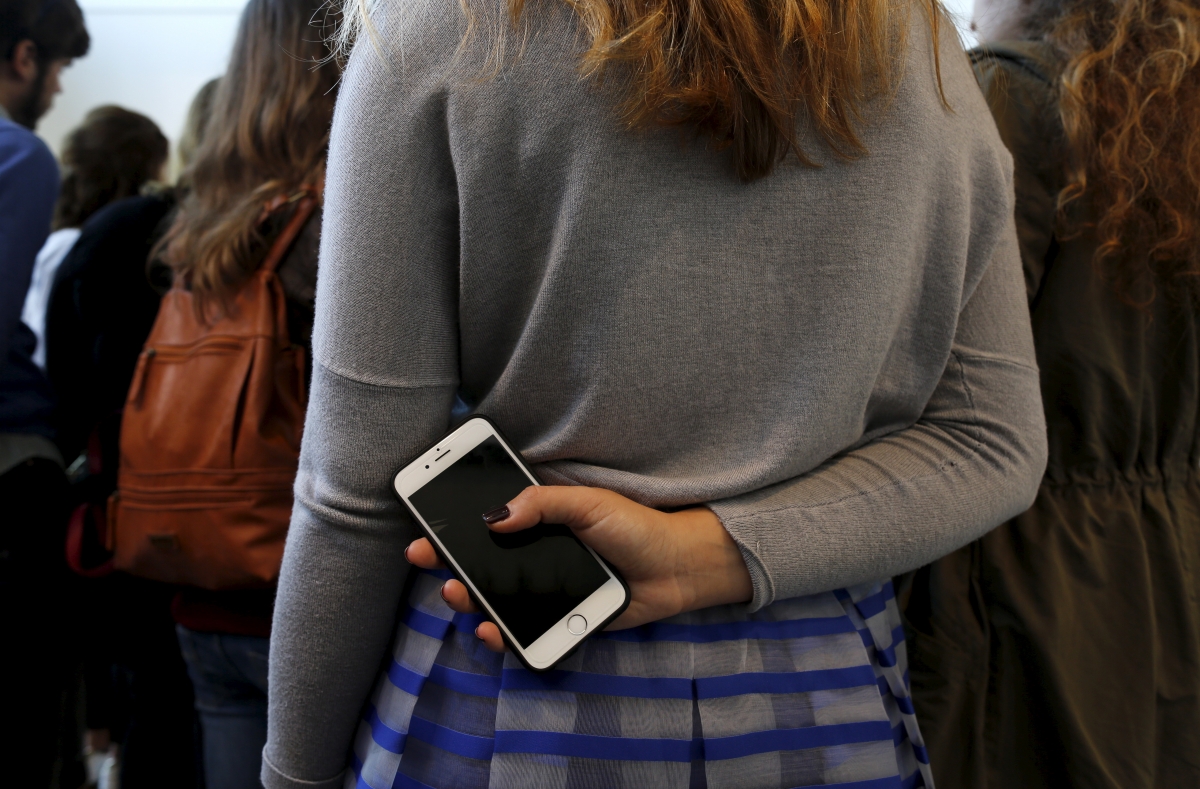 woman holding smartphone behind her back