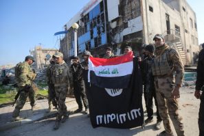 Iraqi security forces hold an Iraqi flag